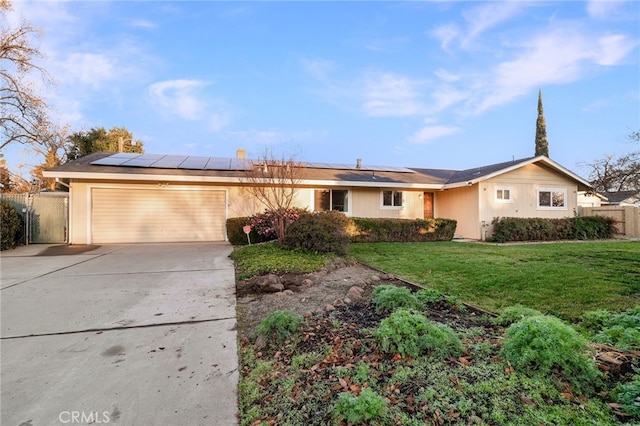 ranch-style house with a garage, a front lawn, and solar panels