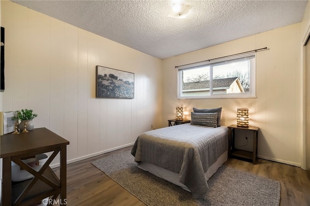 bedroom with a textured ceiling and dark hardwood / wood-style flooring