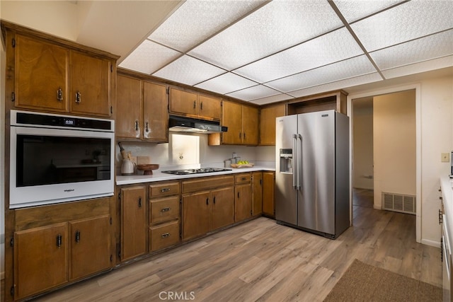 kitchen featuring a drop ceiling, stainless steel appliances, and light hardwood / wood-style floors