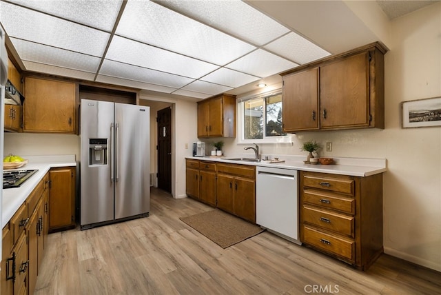 kitchen with sink, a paneled ceiling, stainless steel appliances, and light hardwood / wood-style flooring