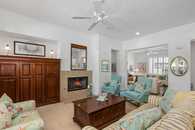 living room featuring light carpet, a tiled fireplace, and ceiling fan