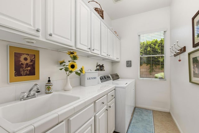 laundry area with washer and clothes dryer, sink, light tile patterned floors, and cabinets