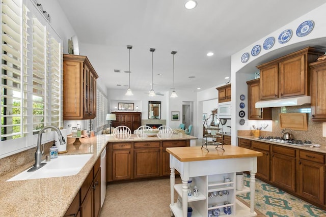 kitchen with white appliances, sink, hanging light fixtures, kitchen peninsula, and butcher block countertops