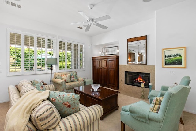 living room featuring ceiling fan and a tiled fireplace