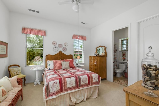 bedroom featuring ceiling fan, light colored carpet, and ensuite bathroom