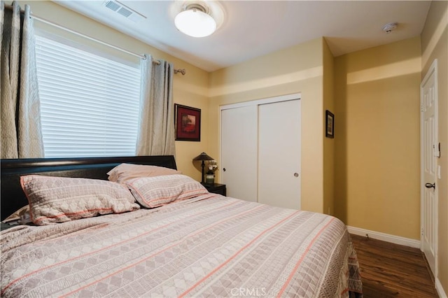 bedroom with dark wood-type flooring and a closet