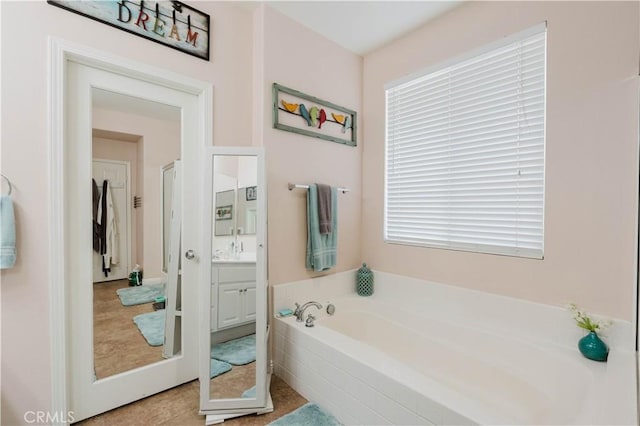 bathroom with a tub to relax in, vanity, and tile patterned floors