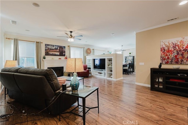 living room with ceiling fan, crown molding, and light hardwood / wood-style floors