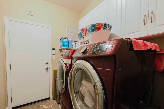 clothes washing area with light tile patterned floors, washer and dryer, and cabinets