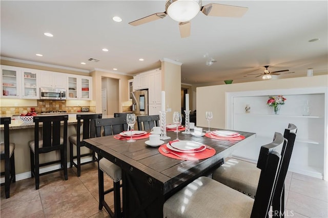 tiled dining area featuring ceiling fan and crown molding