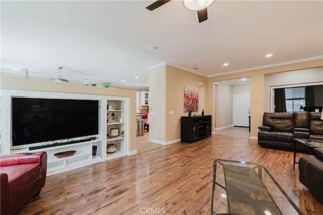 living room with built in shelves, light hardwood / wood-style flooring, and ornamental molding