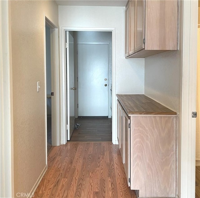 corridor with a textured wall and wood finished floors