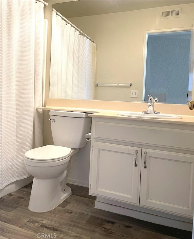 full bathroom with visible vents, toilet, vanity, and wood finished floors