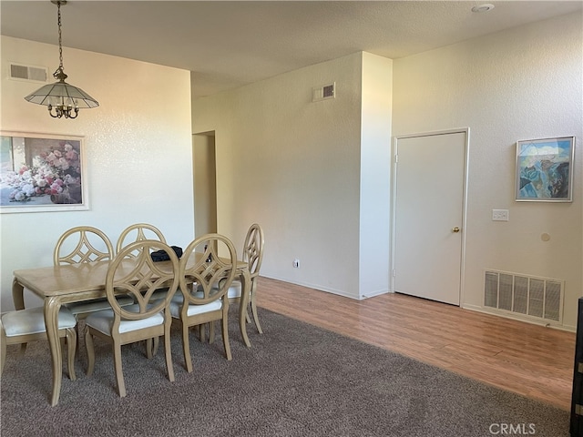 dining area featuring hardwood / wood-style flooring and an inviting chandelier