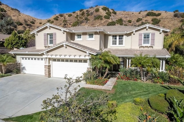 view of front facade featuring a front yard, a garage, and a mountain view