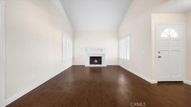 unfurnished living room with a brick fireplace, dark hardwood / wood-style flooring, and lofted ceiling