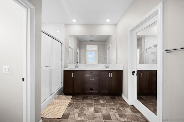 bathroom featuring a shower with shower door and vanity