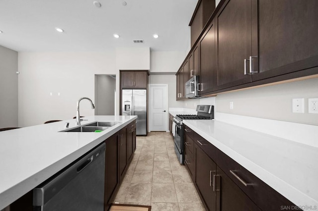 kitchen featuring sink, dark brown cabinetry, stainless steel appliances, and light tile patterned flooring