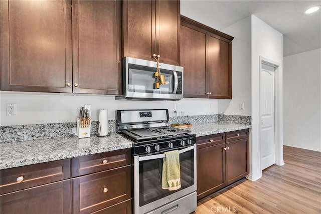 kitchen featuring light hardwood / wood-style flooring, light stone countertops, stainless steel appliances, and dark brown cabinets