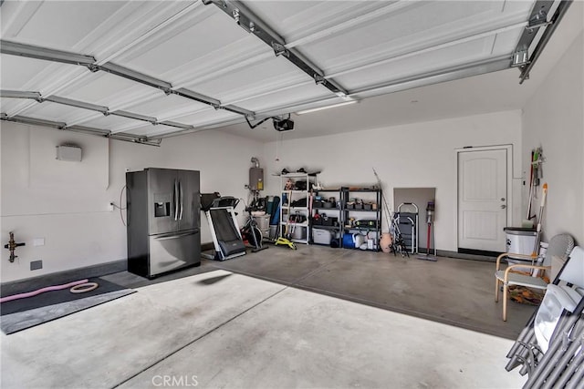 garage featuring stainless steel refrigerator with ice dispenser and a garage door opener