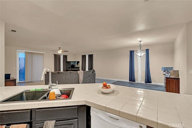 kitchen featuring ceiling fan, dishwasher, tile countertops, sink, and hanging light fixtures