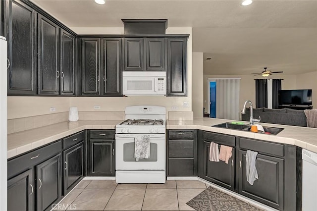 kitchen featuring ceiling fan, tile countertops, sink, white appliances, and light tile patterned floors