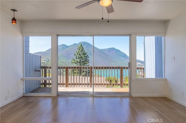 interior space featuring a wealth of natural light, a mountain view, ceiling fan, and wood-type flooring