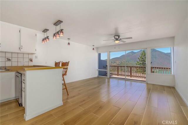 kitchen with a mountain view, light hardwood / wood-style flooring, white cabinets, and hanging light fixtures