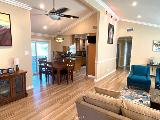 living room with lofted ceiling, ceiling fan, sink, crown molding, and light wood-type flooring