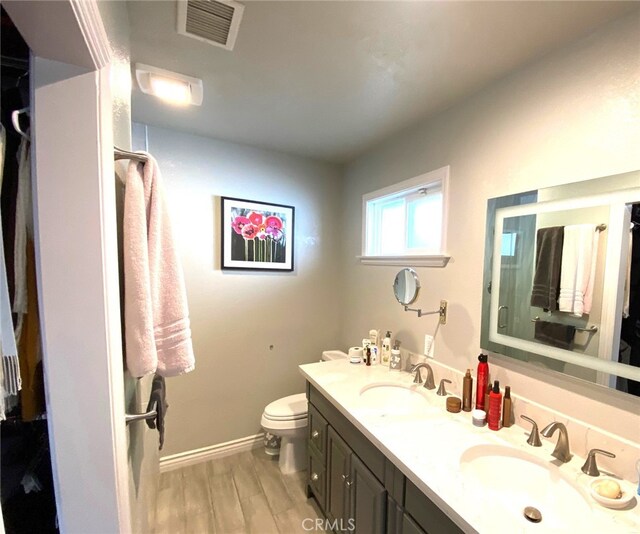 bathroom with toilet, vanity, and wood-type flooring