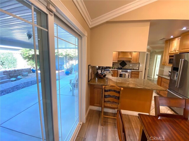 kitchen featuring light hardwood / wood-style floors, kitchen peninsula, a breakfast bar area, stainless steel appliances, and crown molding