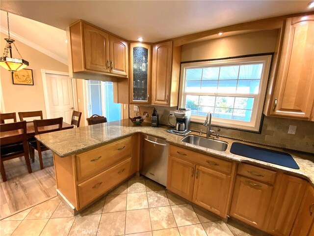 kitchen featuring stainless steel dishwasher, decorative light fixtures, light stone countertops, and sink