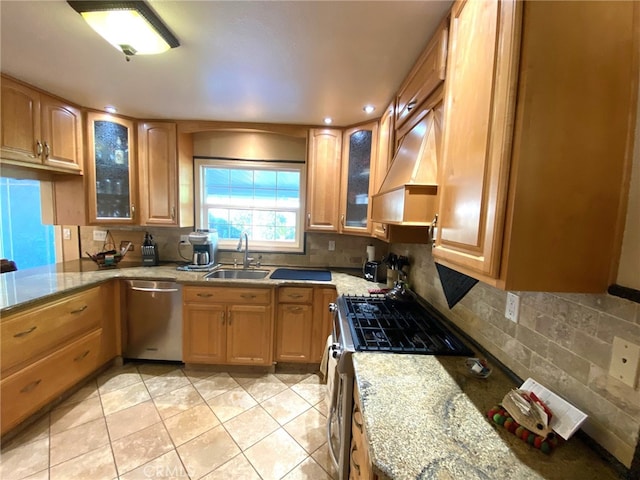 kitchen with tasteful backsplash, sink, light stone countertops, appliances with stainless steel finishes, and custom range hood