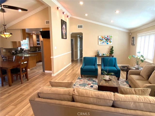 living room featuring lofted ceiling, ceiling fan, light hardwood / wood-style floors, sink, and ornamental molding