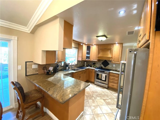 kitchen with tasteful backsplash, premium range hood, a breakfast bar, kitchen peninsula, and stainless steel appliances