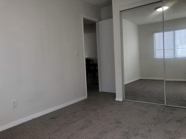 unfurnished bedroom featuring dark carpet and a closet