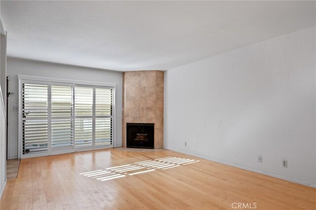 unfurnished living room featuring light wood-type flooring and a tiled fireplace