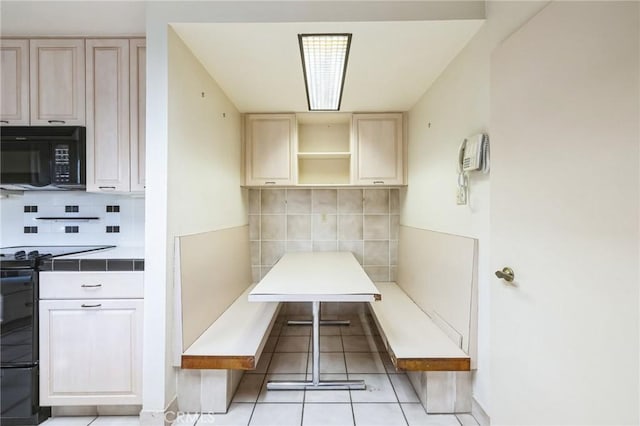 kitchen featuring decorative backsplash, tile countertops, stove, and light tile patterned flooring