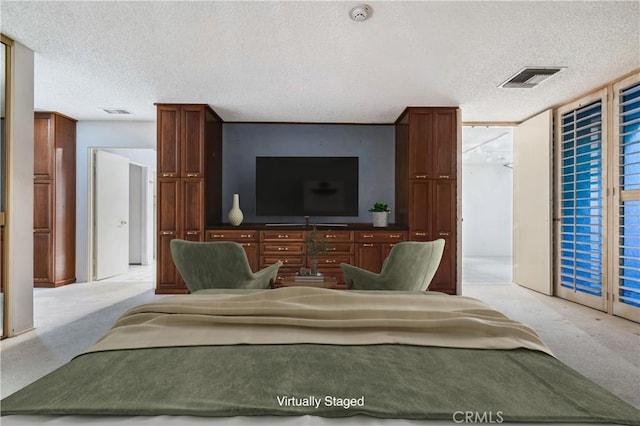 bedroom with access to exterior, a textured ceiling, and light carpet