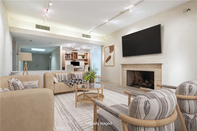 living room featuring a high end fireplace, light tile patterned flooring, and track lighting