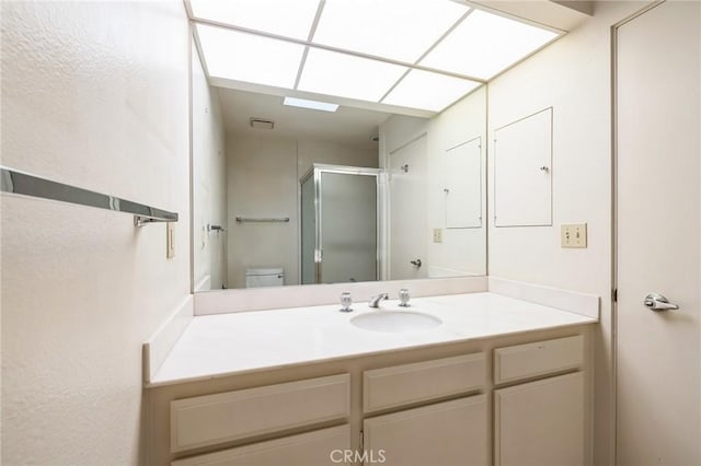 bathroom with a shower with shower door, toilet, and vanity