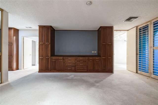 unfurnished living room with light colored carpet and a textured ceiling