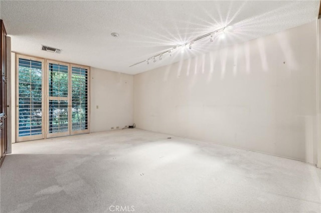 carpeted empty room featuring rail lighting