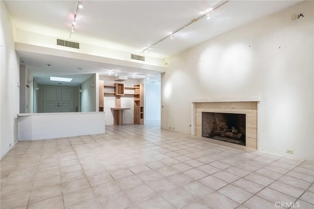 unfurnished living room featuring a high end fireplace and track lighting