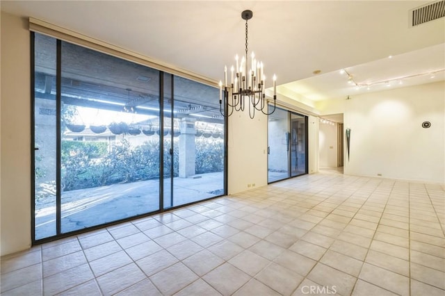 empty room with a wall of windows, light tile patterned flooring, and an inviting chandelier