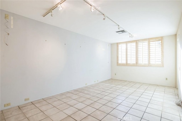 tiled empty room featuring rail lighting