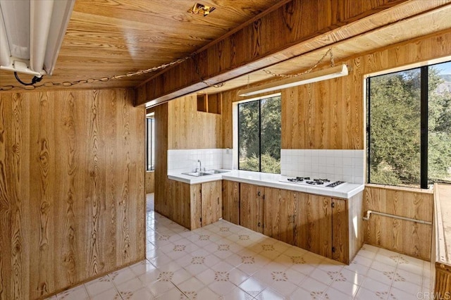 kitchen featuring light countertops, white gas cooktop, a sink, and wooden walls