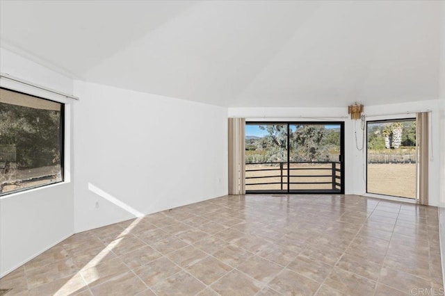 unfurnished room featuring lofted ceiling, tile patterned flooring, and a wealth of natural light