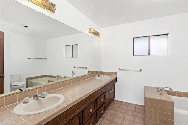 bathroom featuring a garden tub, a sink, and toilet