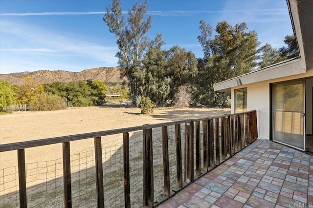 view of patio / terrace featuring a balcony, a mountain view, and fence